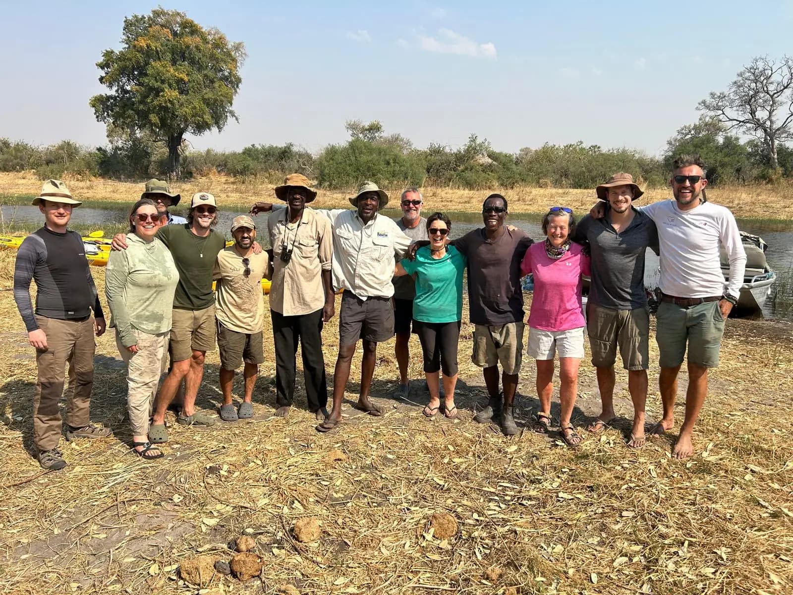 A group standing beside a river with kayaks.