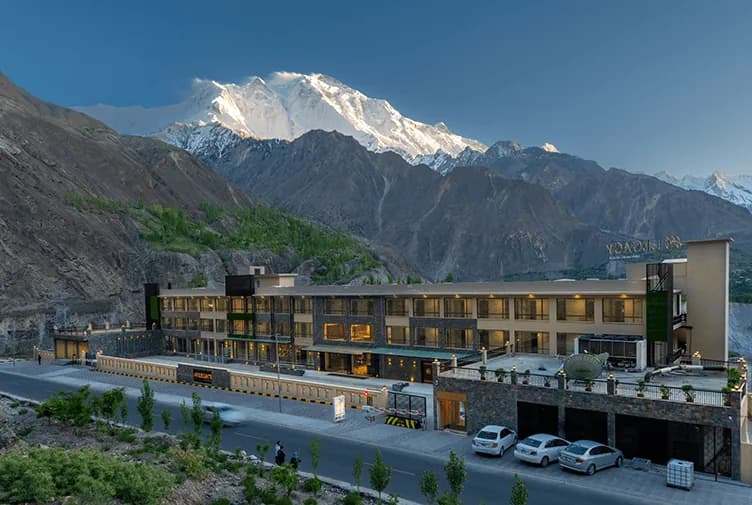 A long hotel building beneath dark foothills and a high snow-covered mountain.